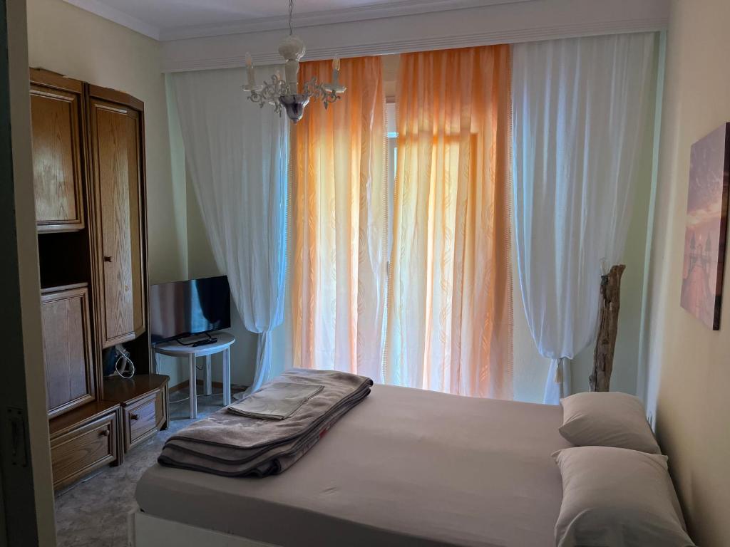 Un dormitorio con una cama y una ventana grande. en Nectarios seaside apartment., en Palaión Tsiflíkion