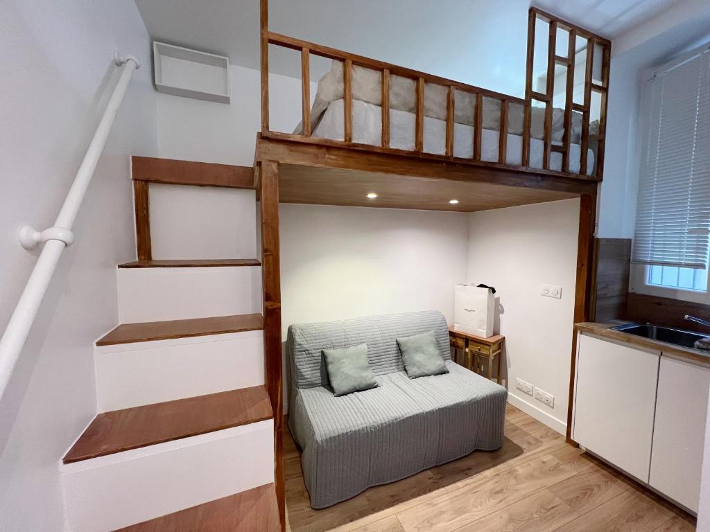Cette chambre comprend une mezzanine avec un canapé. dans l'établissement Charme Cosy au Cœur de Paris, à Paris
