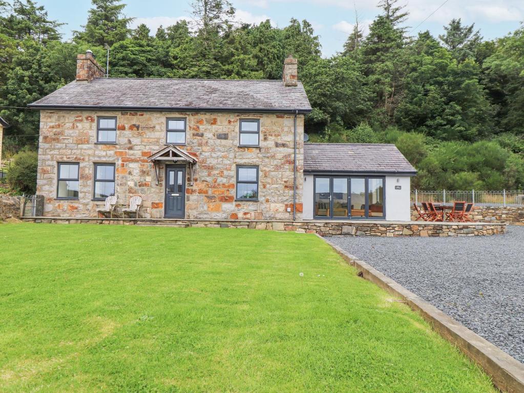 una vecchia casa in pietra con un prato davanti di The Cottage a Pwllheli