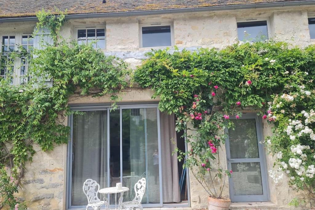 a building with flowers and a table and chairs at Belle maison, 2 chambres dans corps de ferme - logement Raphaël in Villiers-sous-Grez
