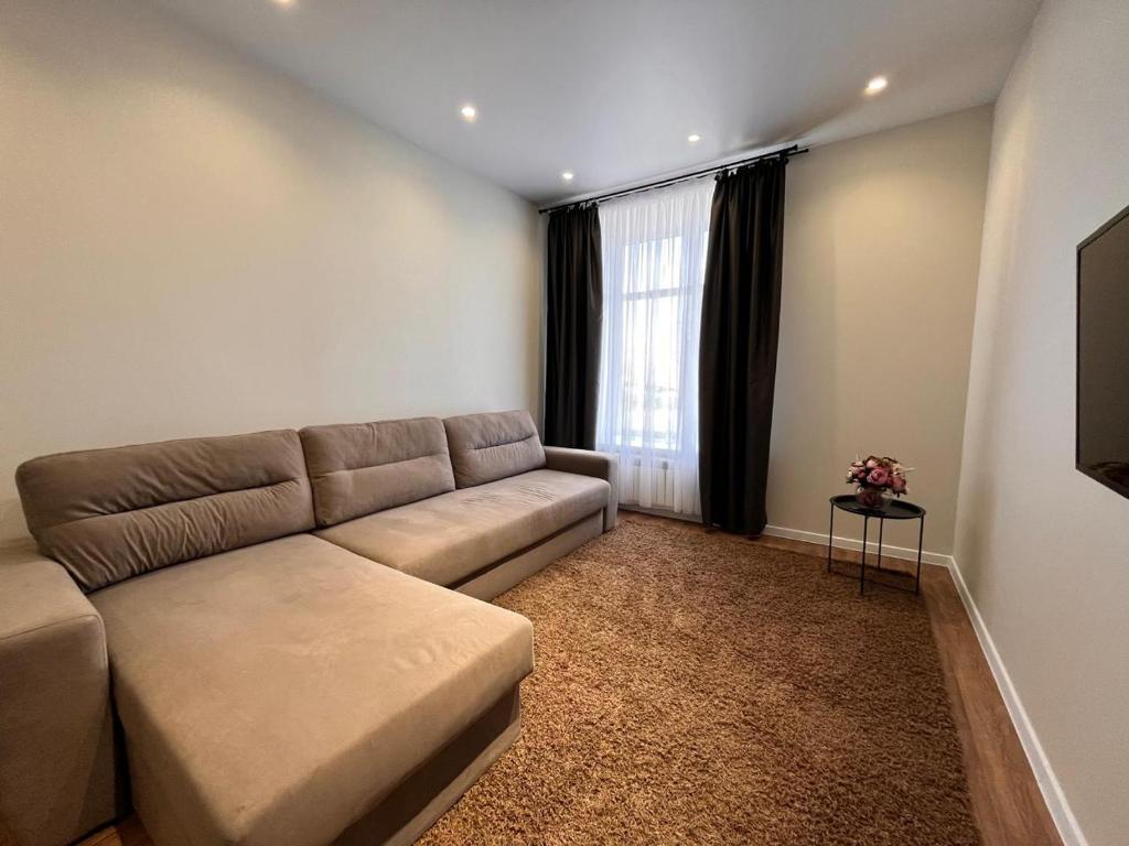 a living room with a couch and a window at Апартаменты ЖК АТАМЕКЕН in Karagandy