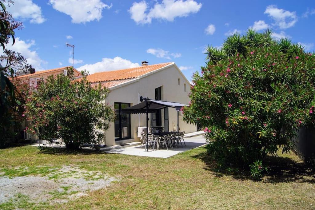 une maison avec un patio avec une table et un parasol dans l'établissement Grande Villa Rénovée à 600 m de la Plage, à Solaro