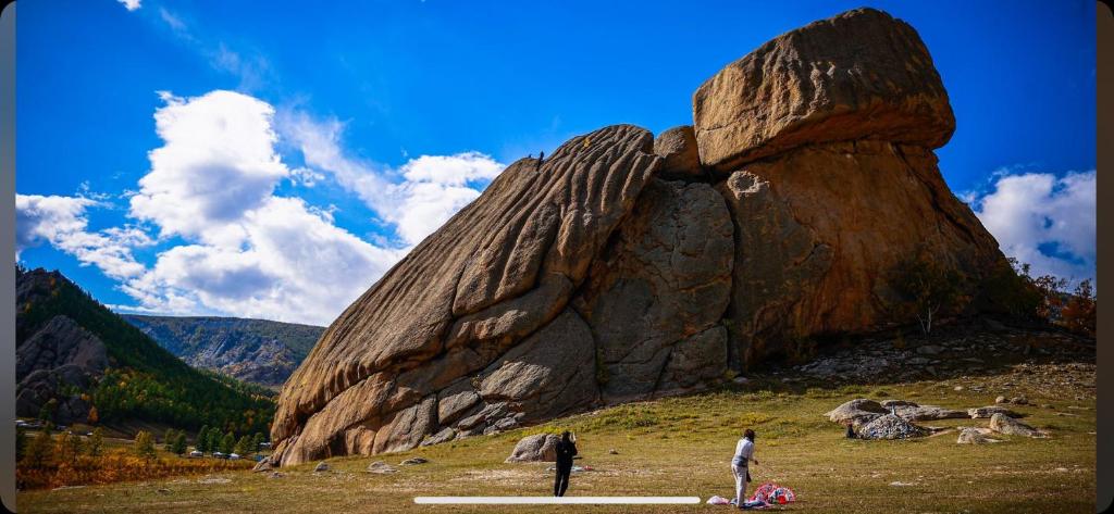 two people standing next to a large rock formation at Old City Guesthouse and Tour Ulaanbaatar Hostel in Ulaanbaatar