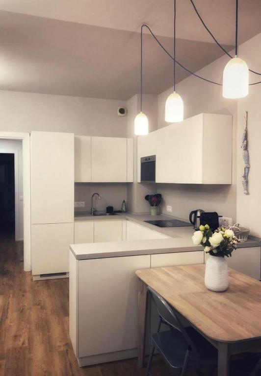 une cuisine avec des placards blancs et une table avec un vase de fleurs dans l'établissement Suite Offenbach FSHH, à Nice