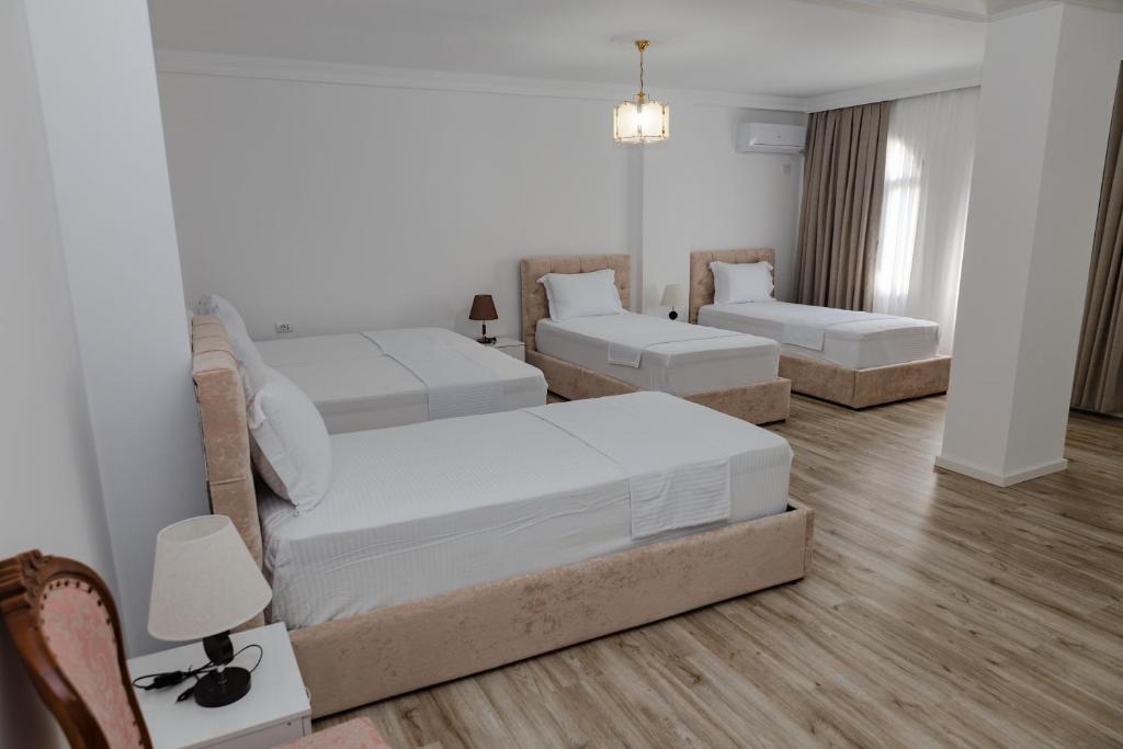 a room with three beds and a table and chairs at Riviera Hotel-City Center in Vlorë