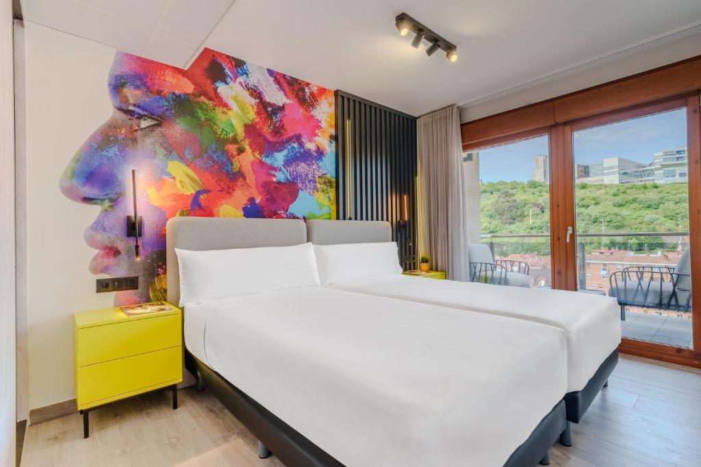 Un dormitorio con una cama blanca y un cuadro en la pared. en Spirit Apartamentos Atxuri, en Bilbao