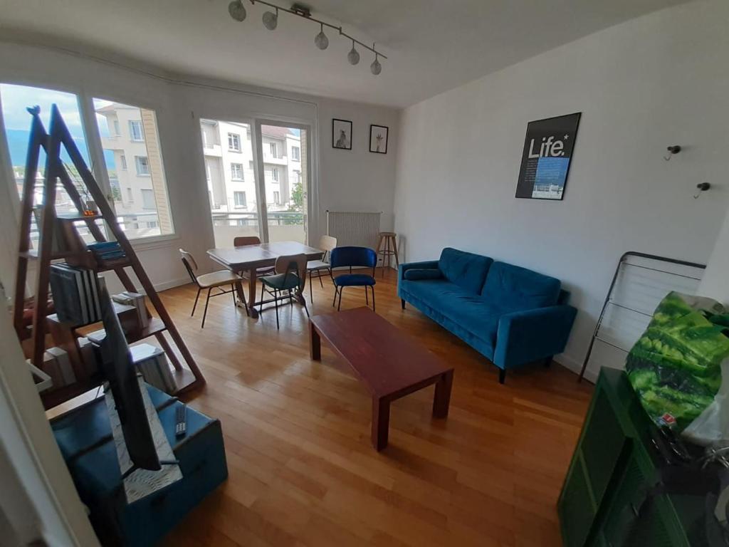 un salon avec un canapé bleu et une table dans l'établissement R'Apparts T2 Cosy et Vintage, à Grenoble