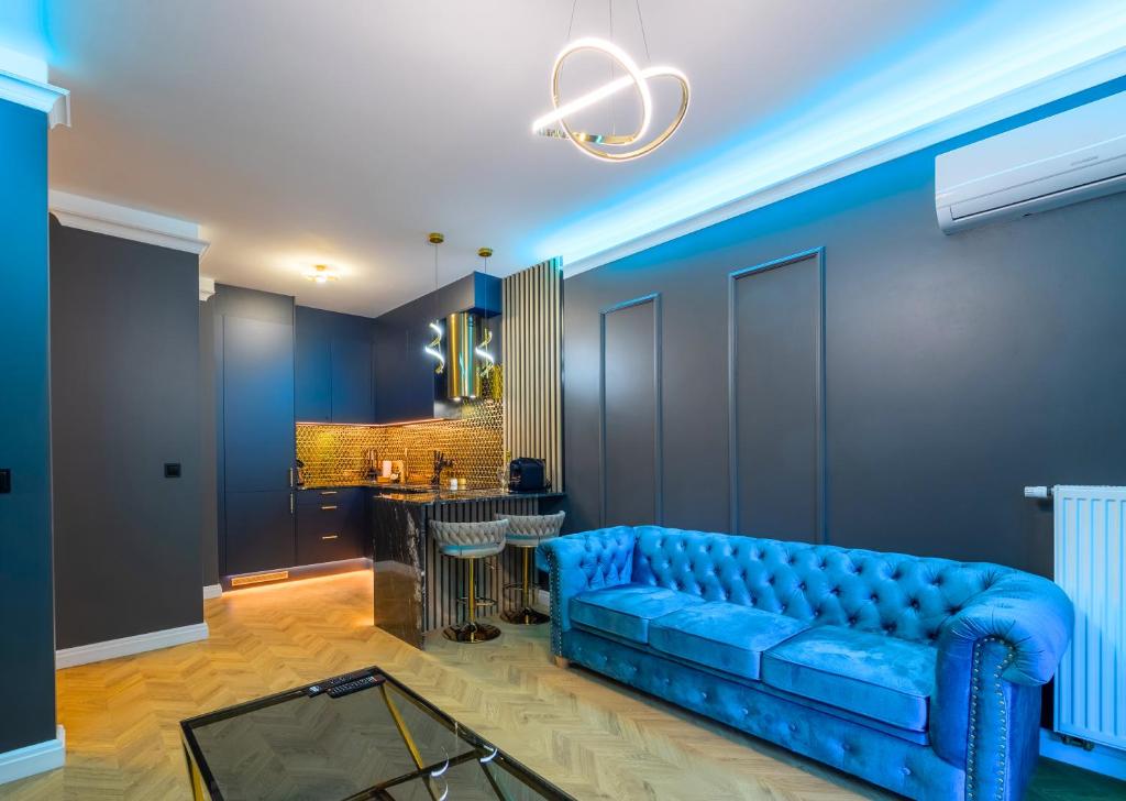 a blue couch in a living room with a bar at Golden Park Aparthotel in Szczecin