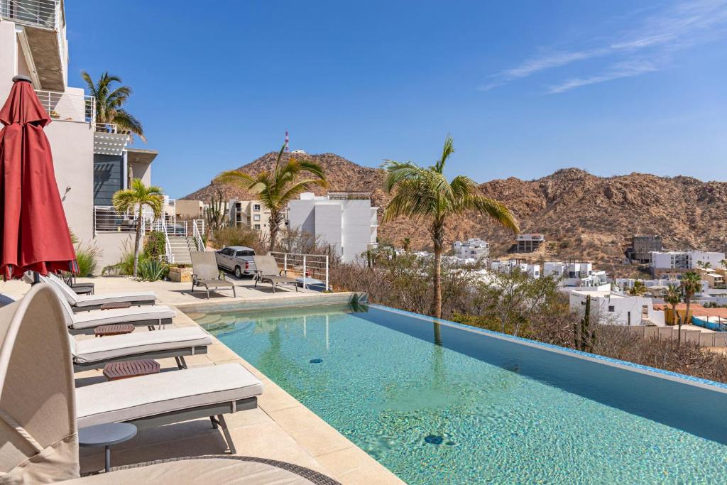 a swimming pool with chairs and palm trees next to a building at 3BR Downtown Condo with Amazing Views in Cabo San Lucas