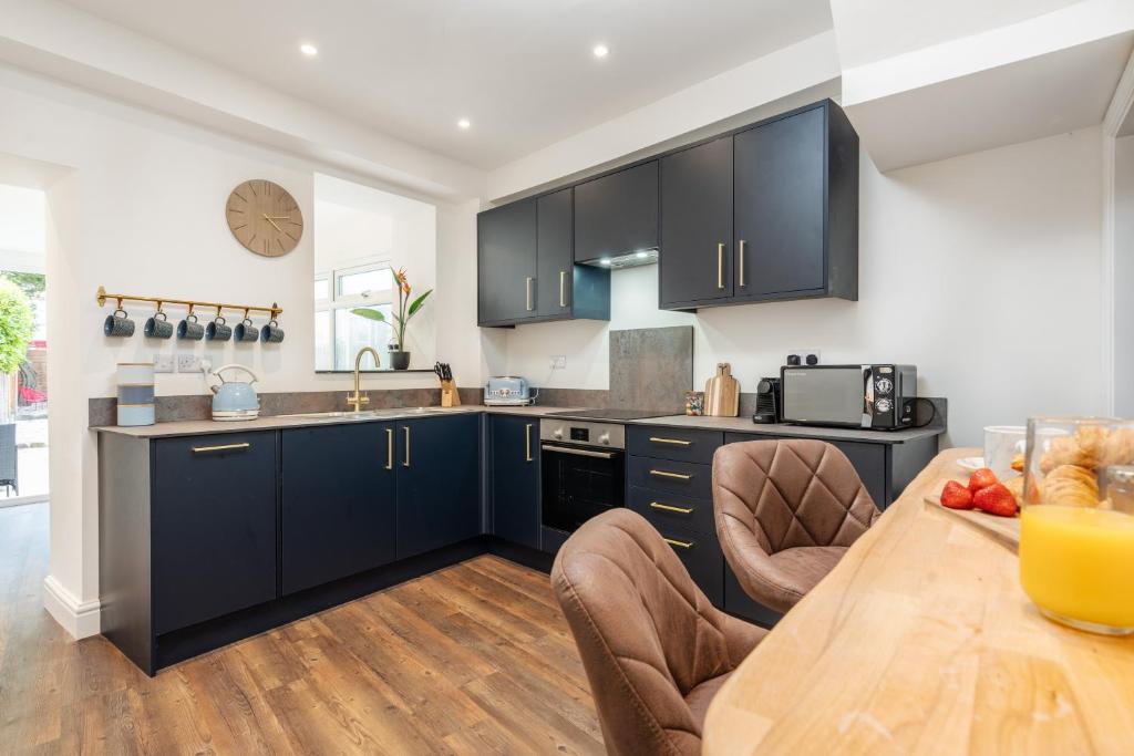 a kitchen with black cabinets and a wooden table at The Tides, 3 bed house Morecambe in Morecambe
