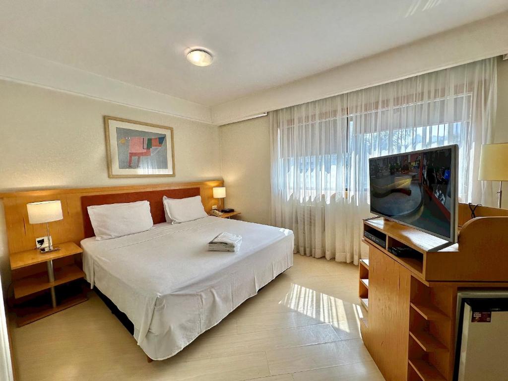 a bedroom with a bed and a flat screen tv at Bienal First Class Flat Service in São Paulo