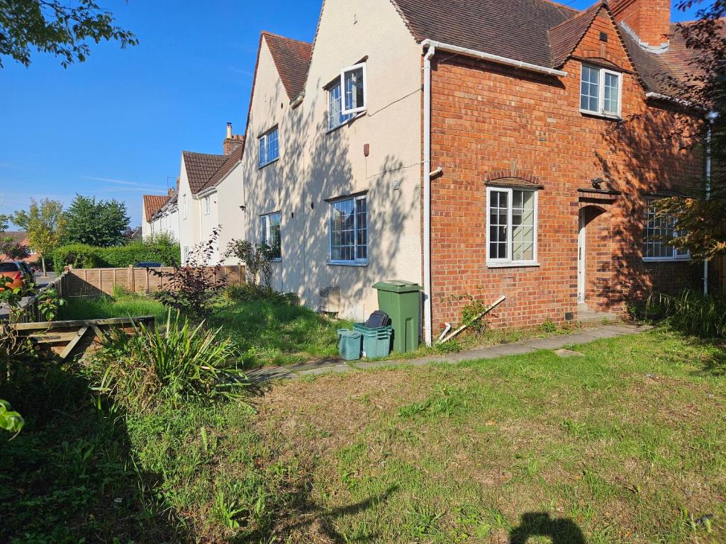 a brick house with a green trash can in the yard at Central Studios 87 Tennyson Road in Cheltenham