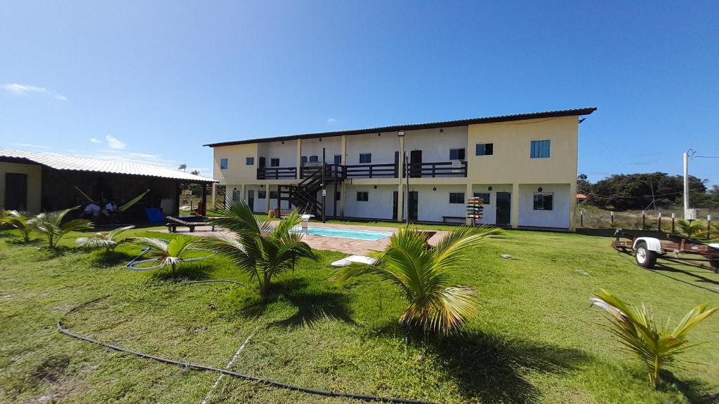 a building with a pool and palm trees in front of it at Flats Vila Bella in Marau