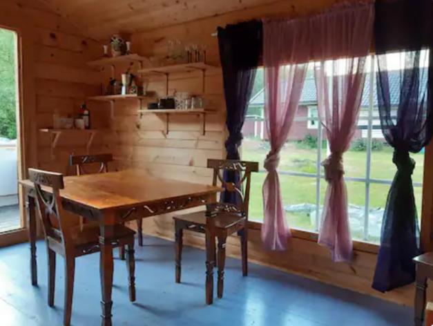 a dining room with a wooden table and chairs and a window at Rentukka - Sähköttömät Yöpymismökit - Off-grid Cottages in Såris