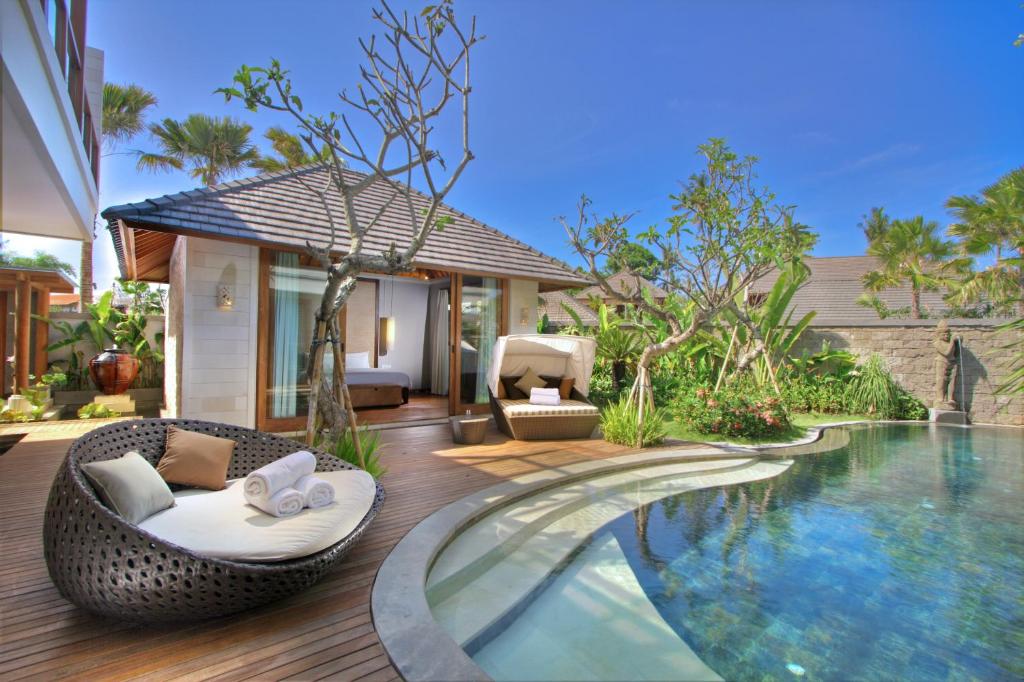 a swimming pool with a wicker chair next to a villa at The Akasha Luxury Villas in Seminyak