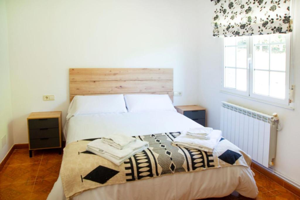 Schlafzimmer mit einem Bett mit einem Kopfteil aus Holz und einem Fenster in der Unterkunft Welcome A Casiña de Arcos de Furcos in Cuntis