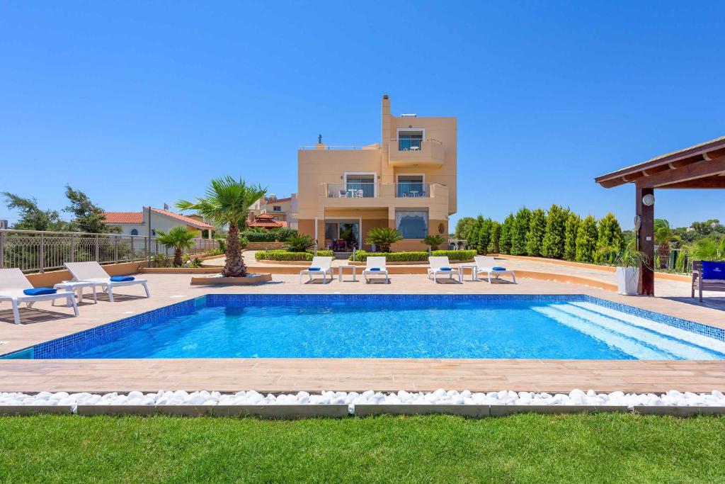 a swimming pool in front of a villa at Aegean Blue Villa in Koskinou