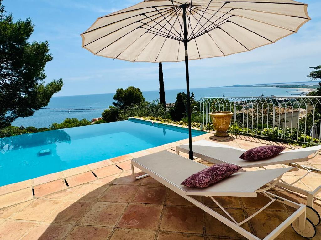 - une table avec un parasol à côté de la piscine dans l'établissement L'équinoxe vue sur la mer, à Sète
