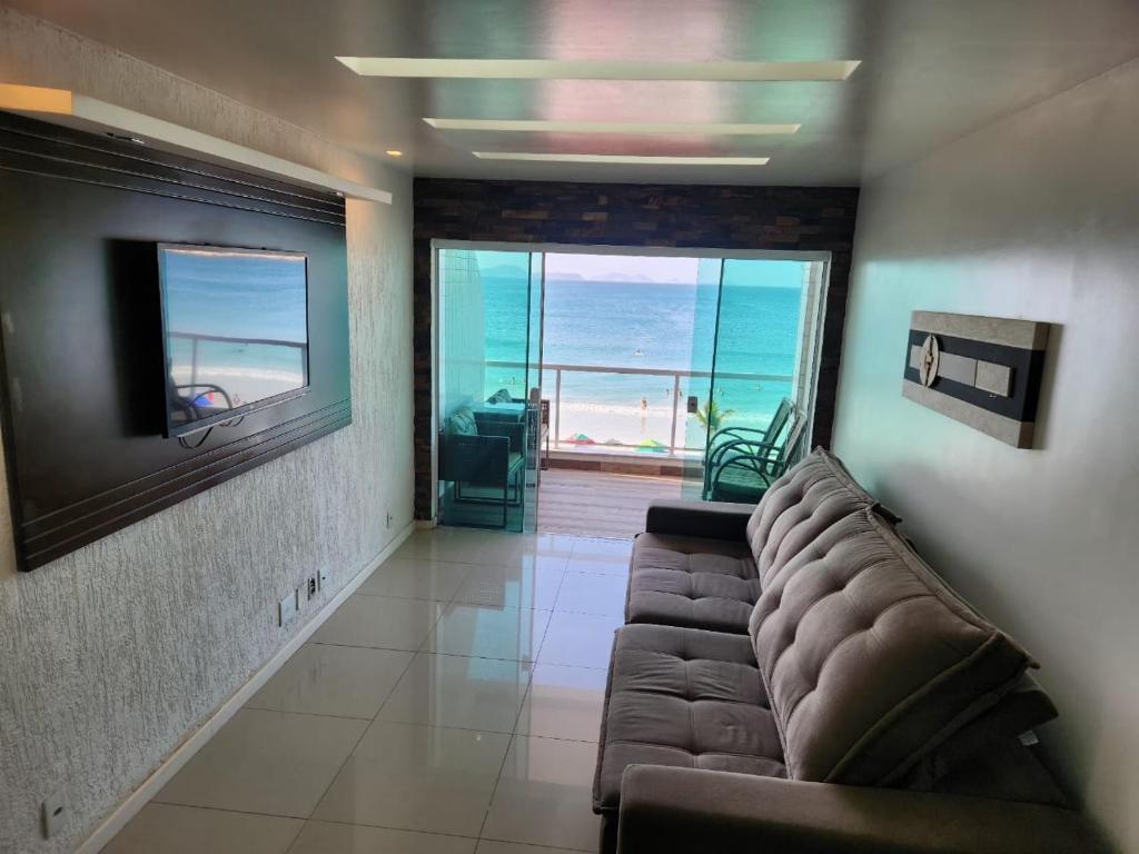 Una sala de estar con un sofá y vista al mar. en Vista Maravilhosa, 3 Quartos, Lazer com Piscina, Churrasqueira e 2 Vagas, en Arraial do Cabo