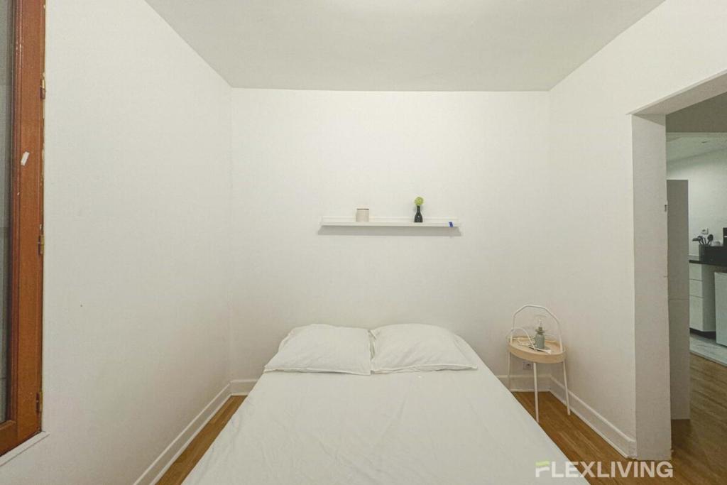 Cette chambre blanche comprend un lit et une étagère. dans l'établissement Flexliving - room - Banquier, à Paris