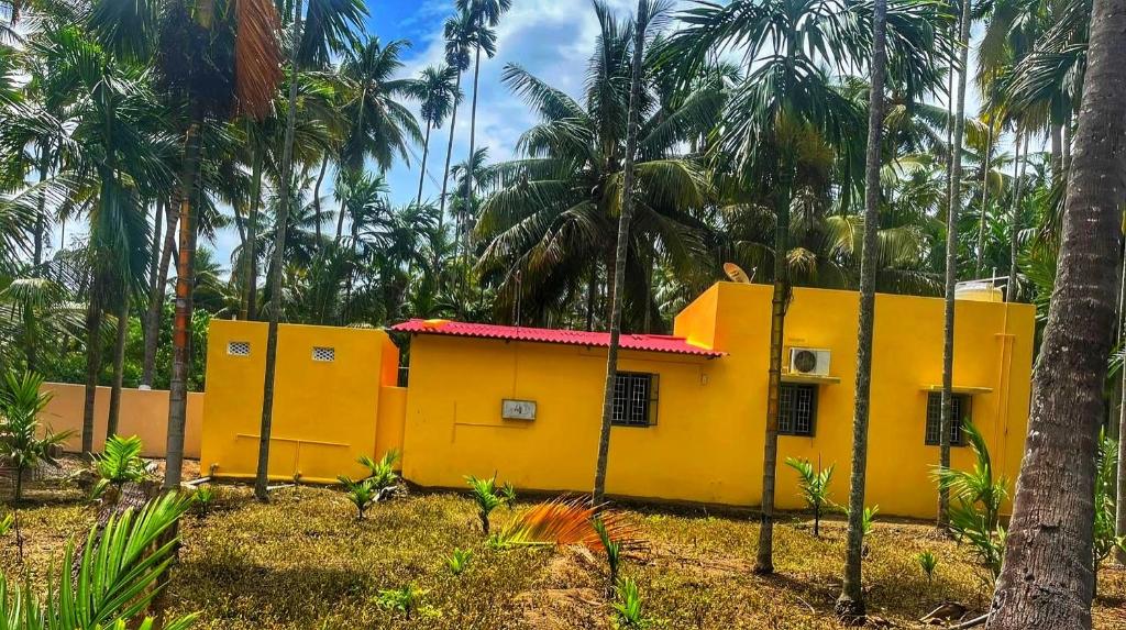 una casa gialla con palme sullo sfondo di Private Villa Inside Coconut Farm By Shivalaya ad Alāndurai
