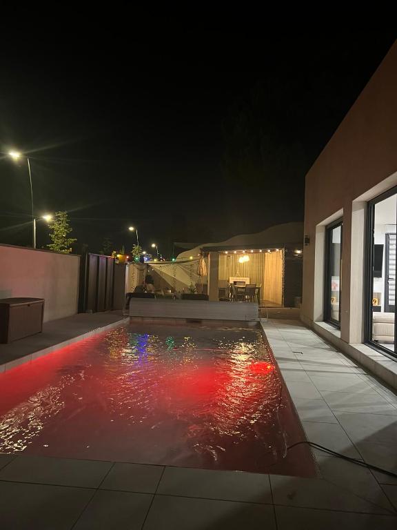 une piscine la nuit avec des lumières rouges et blanches dans l'établissement villa Wamal, à Mauguio