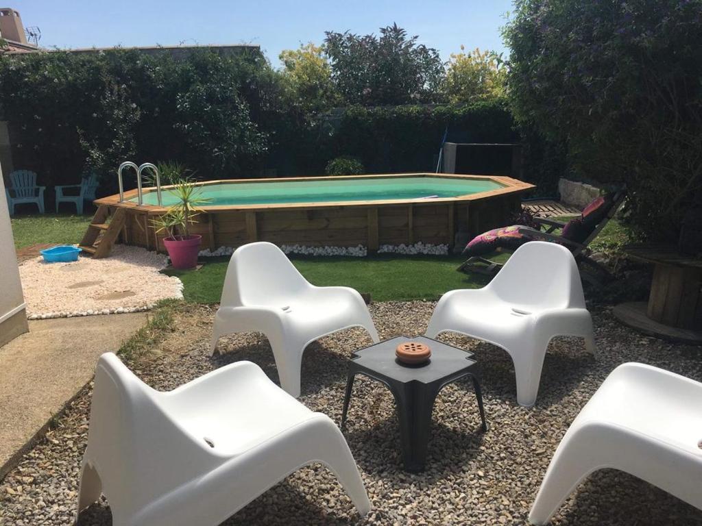 une cour avec des chaises blanches et une piscine dans l'établissement Villa proche mer, montagne, Espagne, à Sallèles-dʼAude