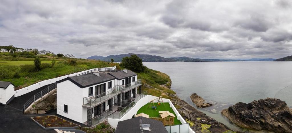 a house on the shore of a body of water at Pierside Apartments Deluxe Accommodation in Portsalon