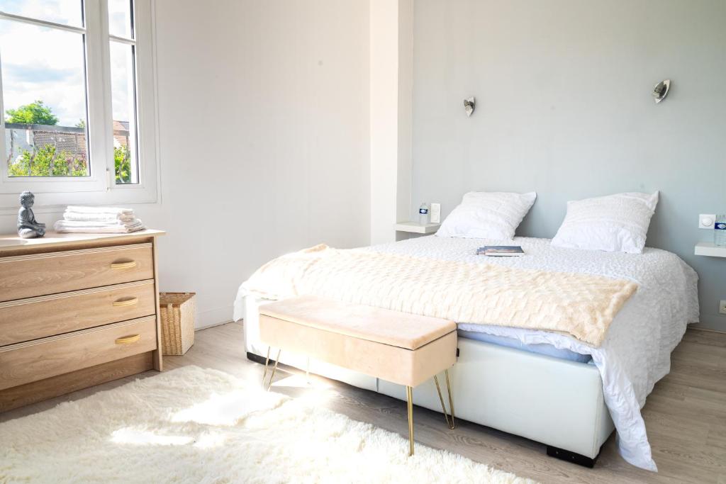 a bedroom with a bed and a dresser and a window at 5 min château Charmante maison et son jardin privé in Versailles