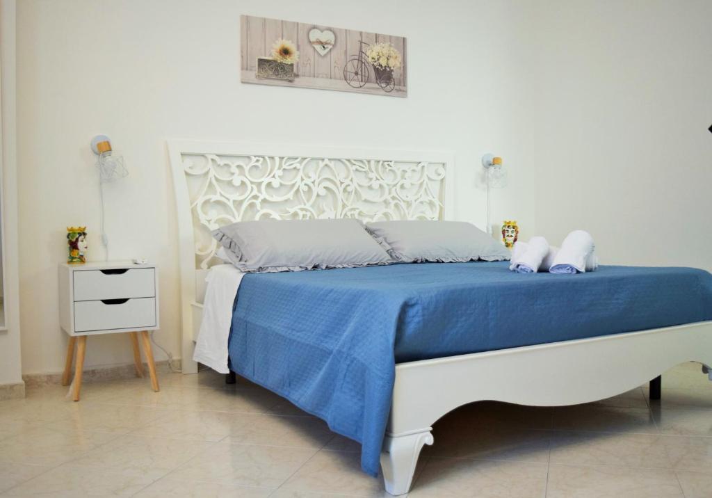 una camera bianca con un letto con una coperta blu di Villa Rosi a Isola delle Femmine