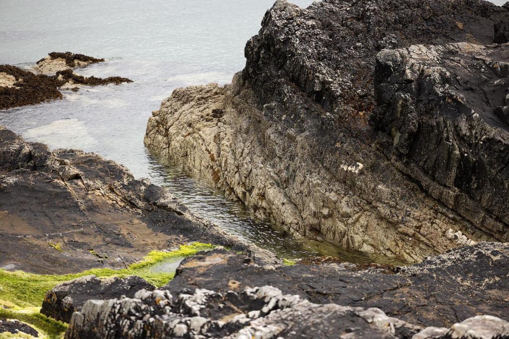 a rocky shoreline with a body of water at Pierside Apartments Deluxe Accommodation in Portsalon