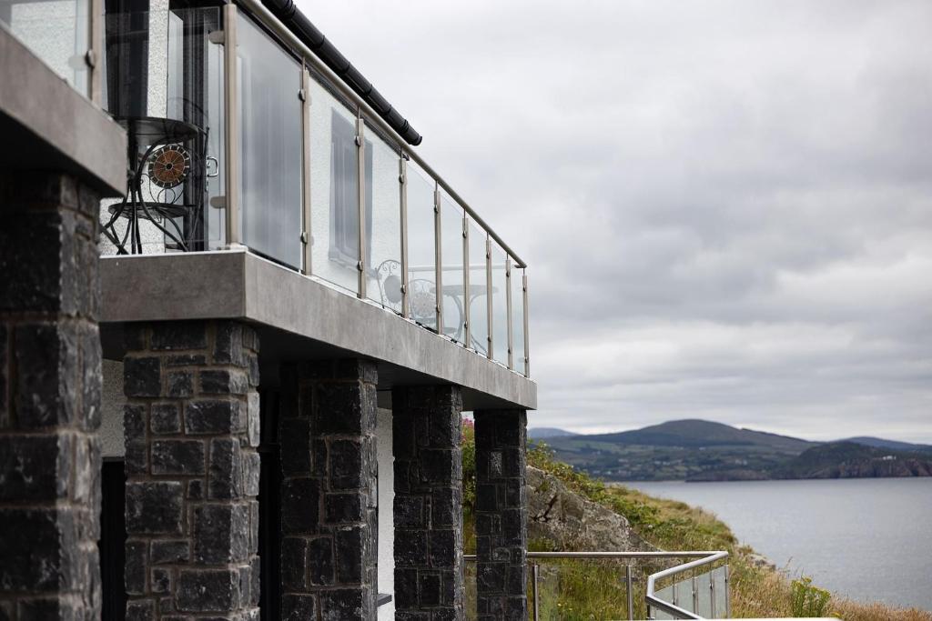 a building with a balcony overlooking a body of water at Pierside Apartments Deluxe Accommodation in Portsalon