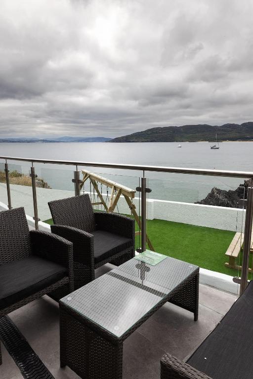 a balcony with a table and chairs and a view of the water at Pierside Apartments Deluxe Accommodation in Portsalon