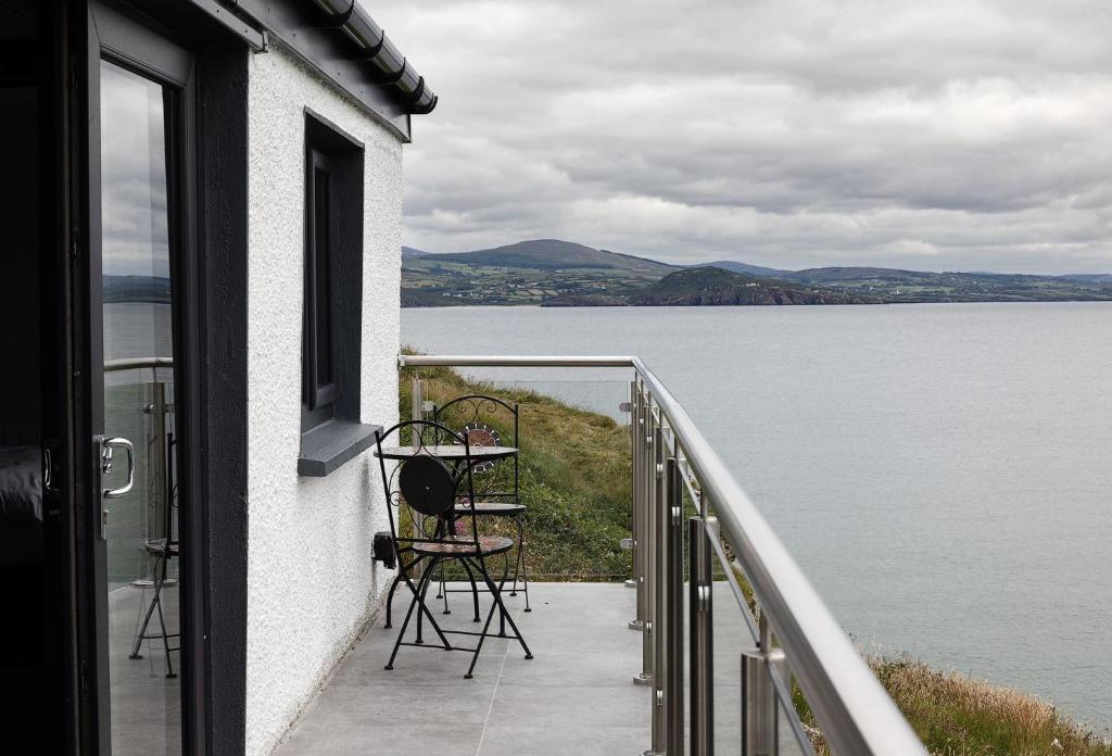 a balcony of a house with a table and chairs at Pierside Apartments Deluxe Accommodation in Portsalon