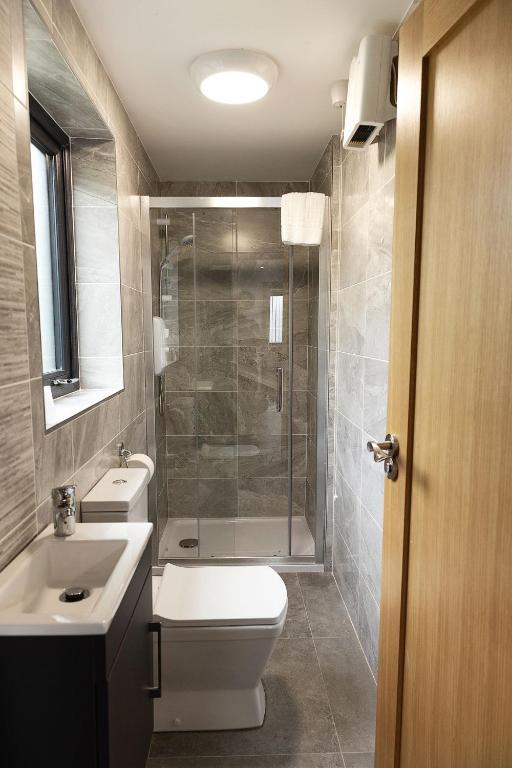 a bathroom with a shower and a toilet and a sink at Pierside Apartments Deluxe Accommodation in Portsalon