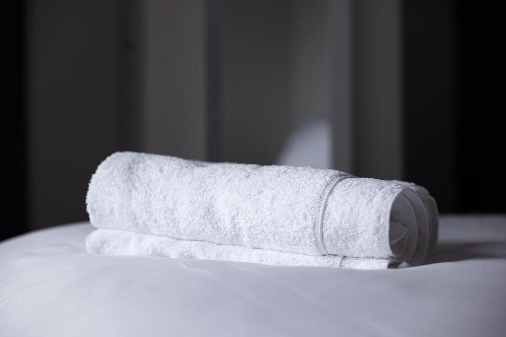 a stack of white towels sitting on top of a bed at Pierside Apartments Deluxe Accommodation in Portsalon