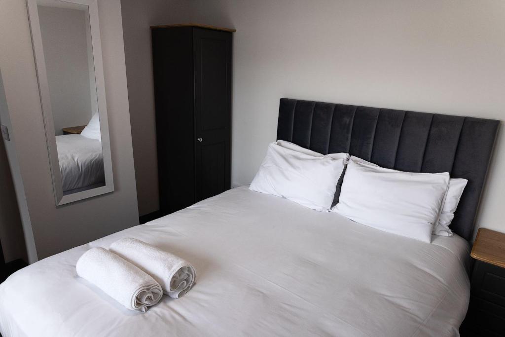 a white bed with two towels on top of it at Pierside Apartments Deluxe Accommodation in Portsalon