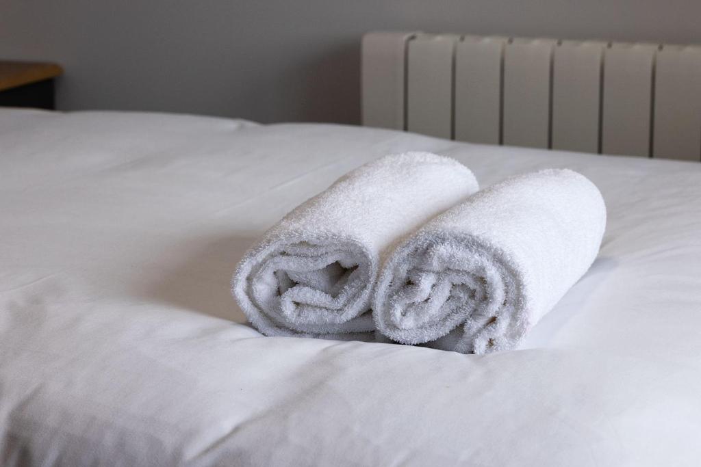 a pile of towels sitting on top of a bed at Pierside Apartments Deluxe Accommodation in Portsalon