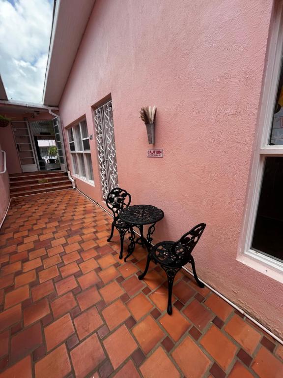 two chairs and a table in front of a pink wall at The Monteray Hotel in Christ Church