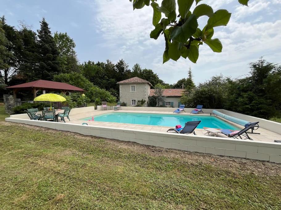 une grande piscine avec des chaises et un parasol dans l'établissement Vaste propriété de charme au cœur du Périgord vert, à Siorac-de-Ribérac