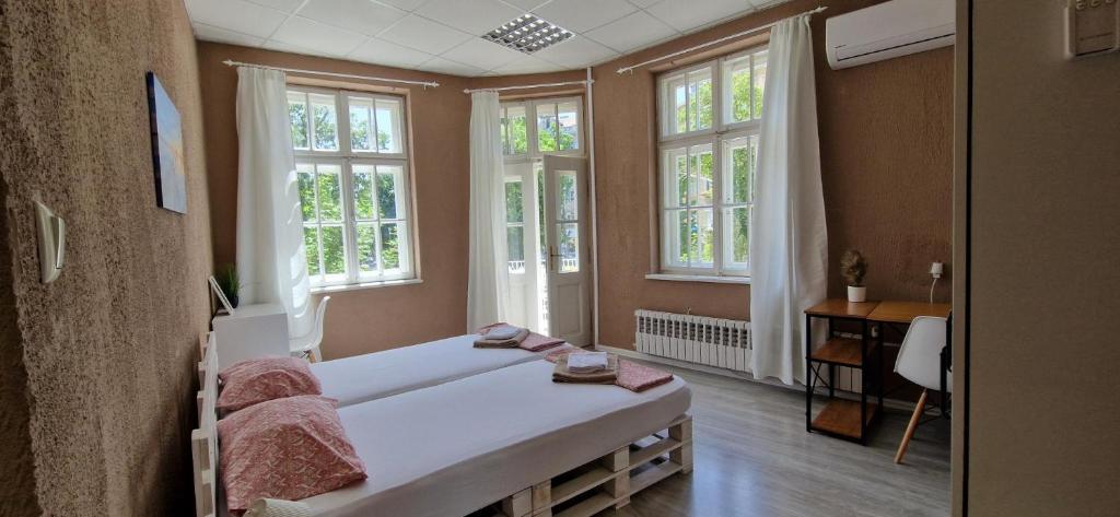 a bedroom with a large white bed and windows at Lambo's Corner Varna - Guest Rooms in Varna City