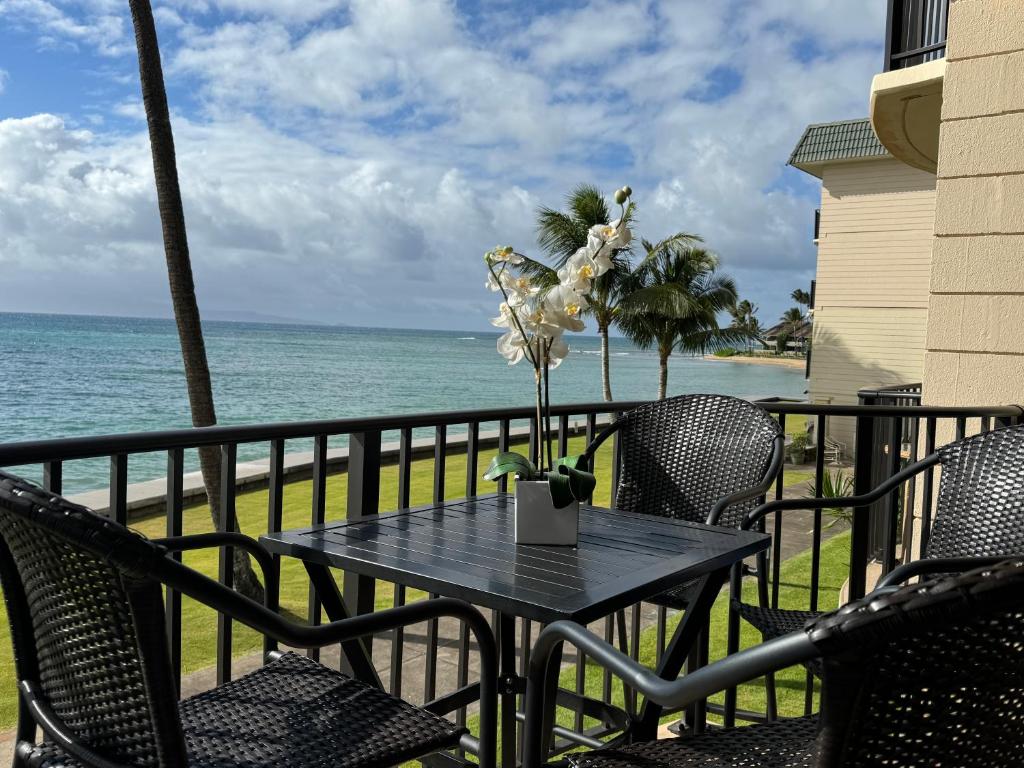 a table and chairs on a balcony with the ocean at Tropical Hawaiian Oceanfront - indigomaui - KR210 in Kahana