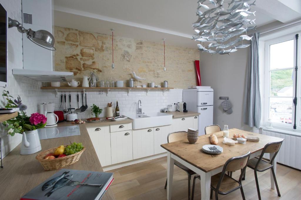 une cuisine avec une table en bois et une salle à manger dans l'établissement Appartement vue port, à Port-en-Bessin-Huppain