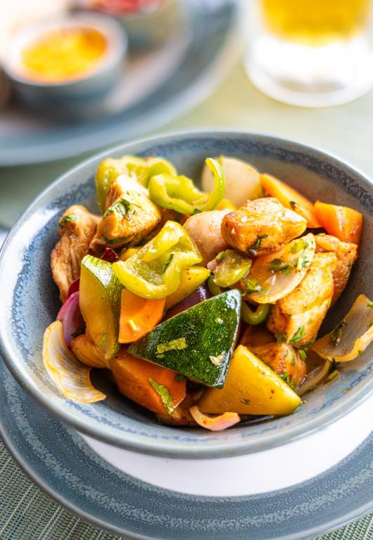 a blue bowl of food with vegetables on a table at Gaia Riverlodge in San Ignacio