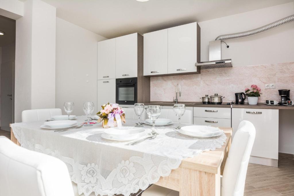 Biała kuchnia ze stołem i białymi szafkami w obiekcie Pool Apartment Bakija 2 - Happy Rentals w Pakoštane