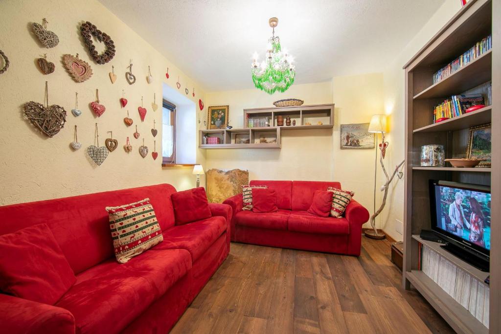 a living room with red couches and a tv at Baita La Ciaburna skiing nearby - Happy Rentals in Bardonecchia