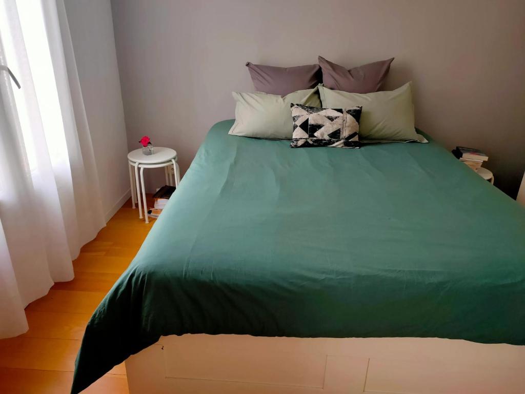 a bed with a green comforter in a bedroom at Appartement moderne à Clichy, 35 m², idéal pour 4 personnes. in Clichy