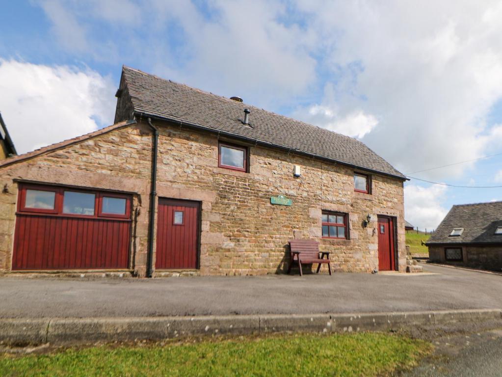 a brick building with red doors and a bench at Downsdale Cottage in Flash