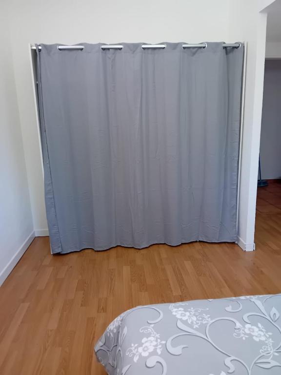 1 dormitorio con cortina blanca y suelo de madera en Residence L&M, en Vétraz-Monthoux