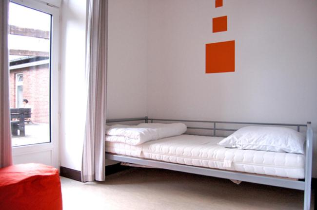 a bed in a room with a white bedspread at Hostel Flensburg in Flensburg
